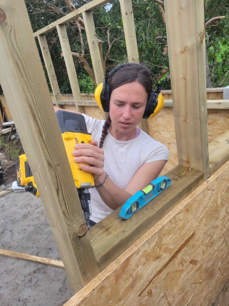 Lydia Paleschi working on the timber frame of a garden room